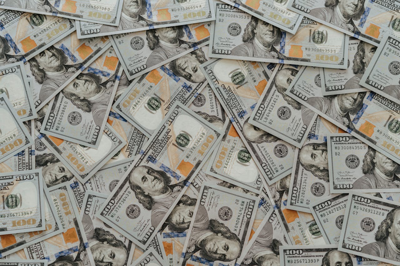US hundred dollar bills scattered in abundance creating a financial backdrop.